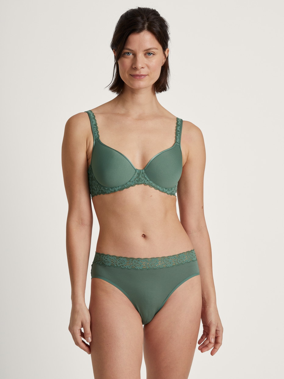 Damen-Model trägt Spacer-BH mit Bügel, Komfort Rücken aus Polyamid in Grün, Spitze aus Serie Natural Comfort Lace von CALIDA, Outfit