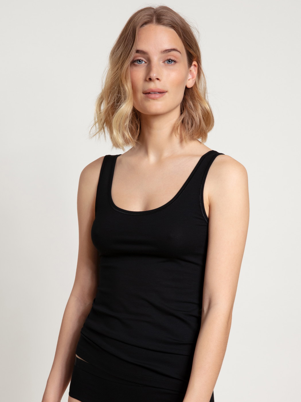 Women model is wearing Tank Top, 2-Pack made of Cotton in Black, Unicoloured from the Benefit Women series by CALIDA, Front view