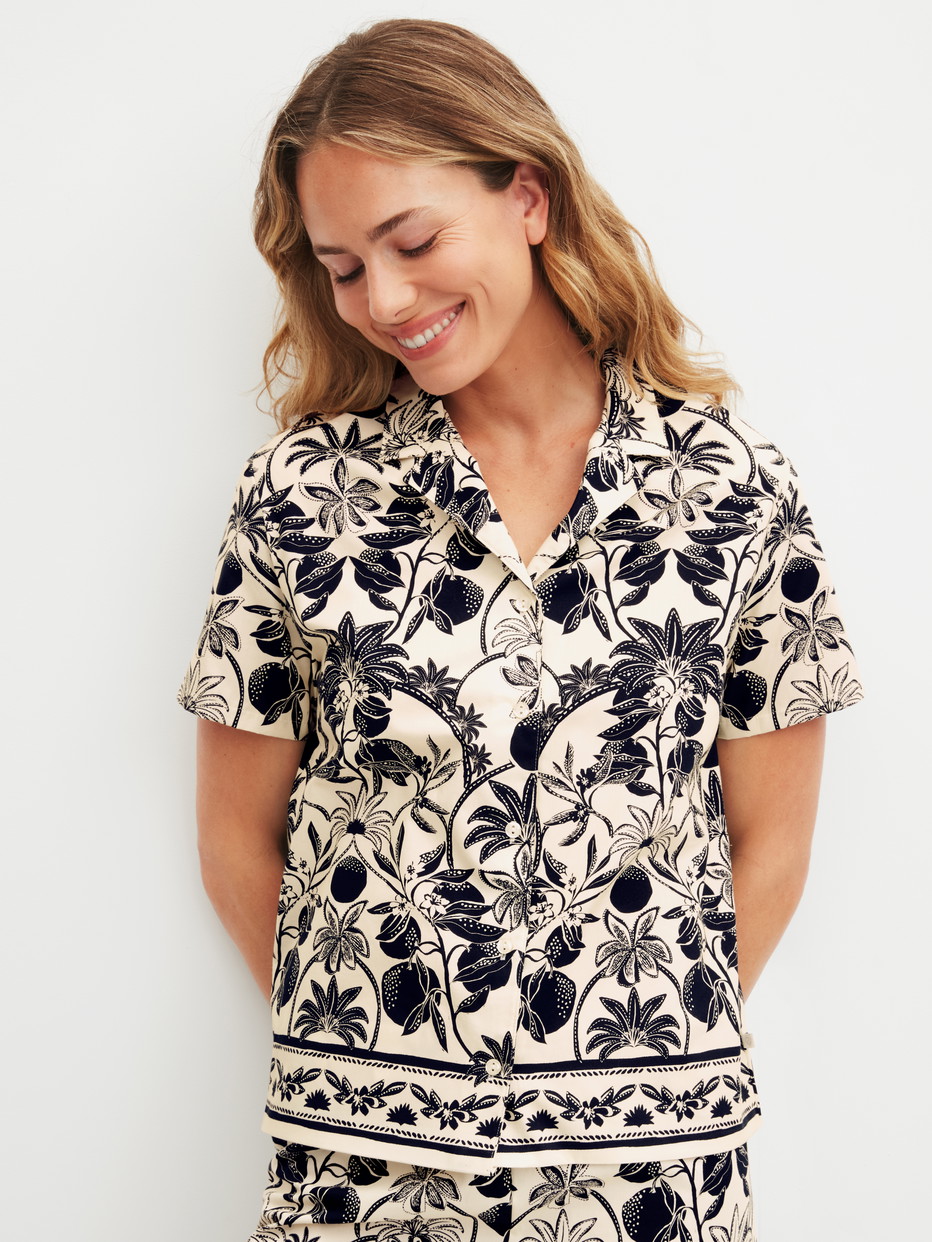 Damen-Model trägt Kurzarm-Shirt mit Knöpfen aus 100% Baumwolle in Schwarz, Floral aus Serie Favourites Layering von CALIDA, Vorderansicht