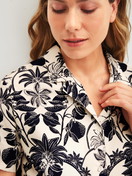 Damen-Model trägt Kurzarm-Shirt mit Knöpfen aus 100% Baumwolle in Schwarz, Floral aus Serie Favourites Layering von CALIDA, Detail