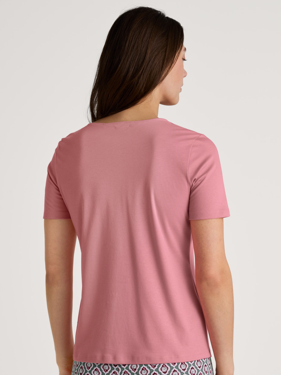 Damen-Model trägt Kurzarm-Shirt, V-Neck aus 100% Baumwolle in Rosa, Einfarbig aus Serie Favourites Ground von CALIDA, Rückansicht