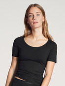 Damen-Model trägt T-Shirt, Rundhals aus Baumwolle in Schwarz, Einfarbig aus Serie Natural Comfort von CALIDA, Vorderansicht