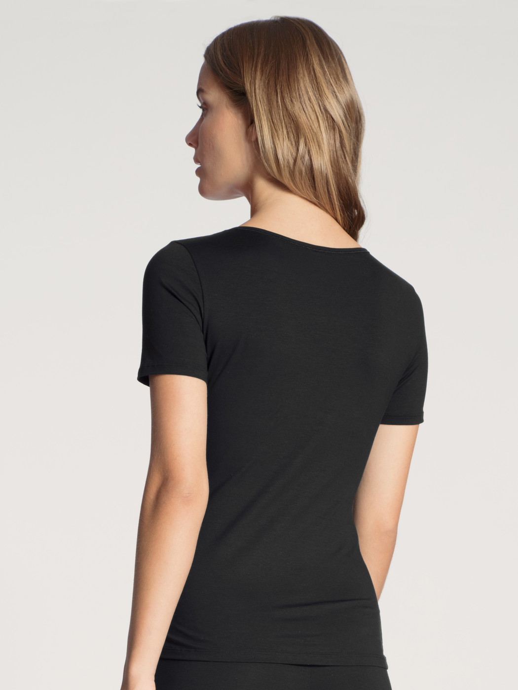 Damen-Model trägt T-Shirt, Rundhals aus Baumwolle in Schwarz, Einfarbig aus Serie Natural Comfort von CALIDA, Rückansicht