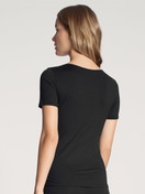 Damen-Model trägt T-Shirt, Rundhals aus Baumwolle in Schwarz, Einfarbig aus Serie Natural Comfort von CALIDA, Rückansicht