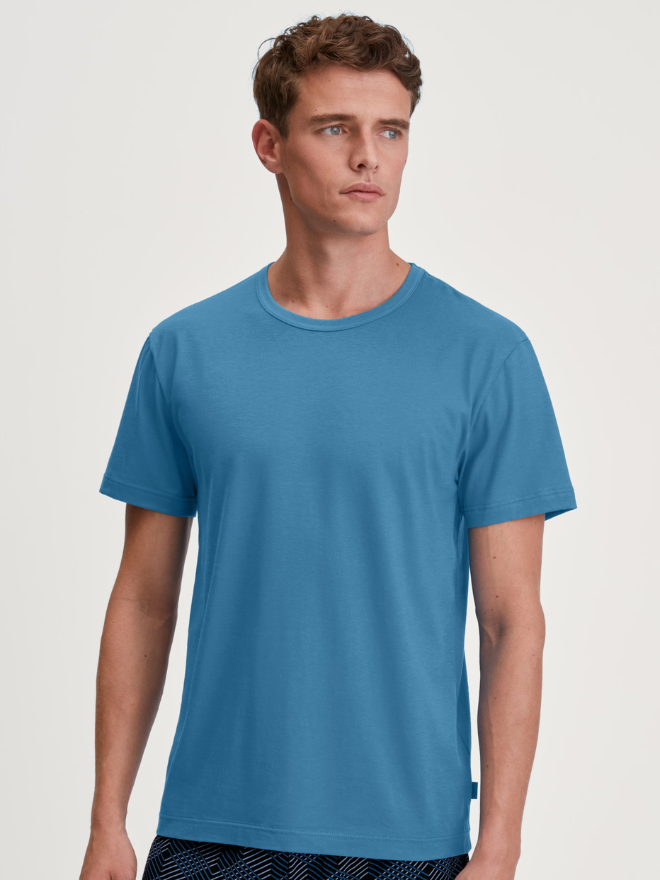 La modella / Il modello Uomo indossa Maglietta a maniche corte in 100% cotone di colore Blu, Tinta unita, della serie RMX Sleep Leisure di CALIDA, Vista frontale