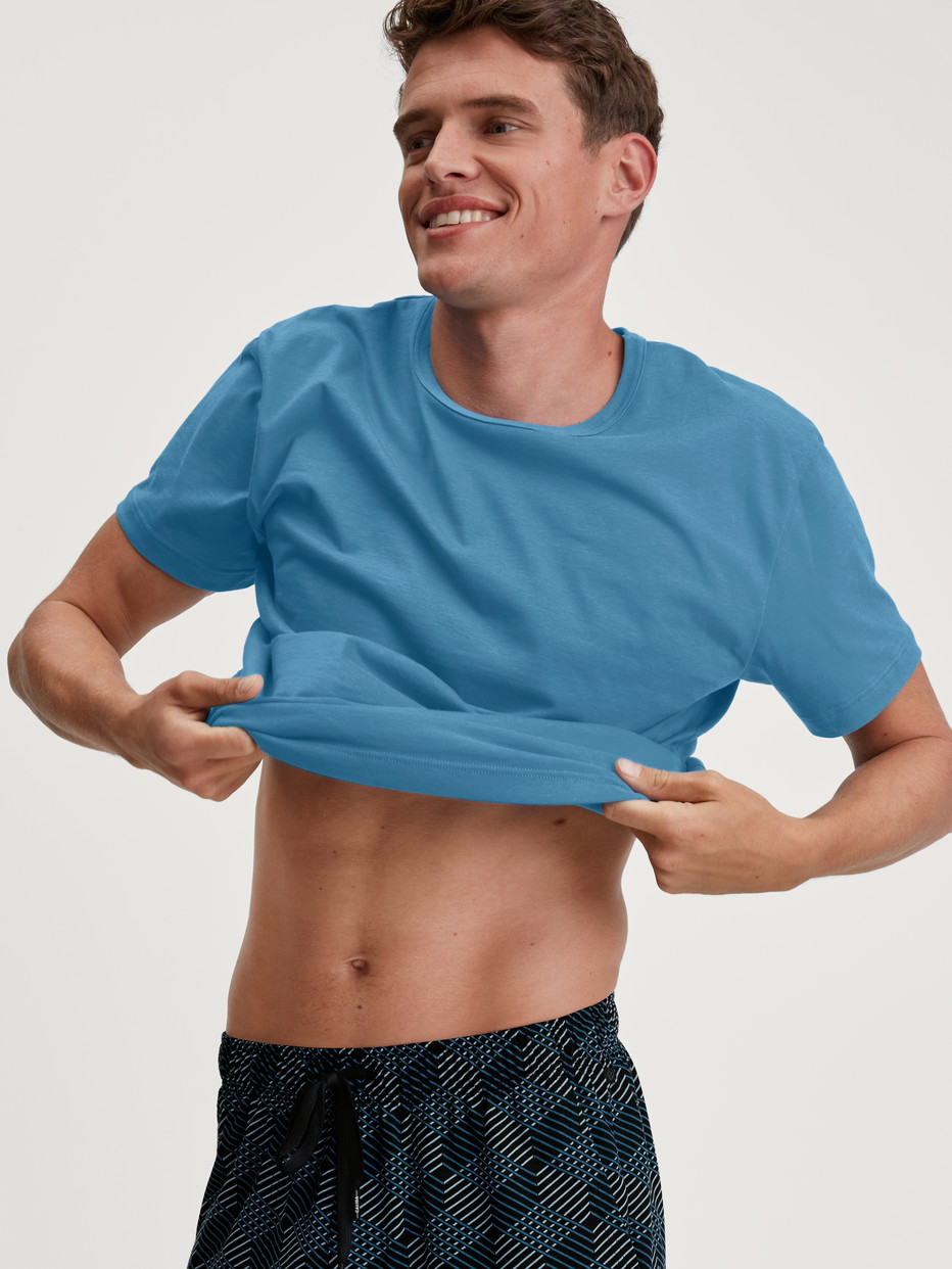 La modella / Il modello Uomo indossa Maglietta a maniche corte in 100% cotone di colore Blu, Tinta unita, della serie RMX Sleep Leisure di CALIDA, Immagine aggiuntiva