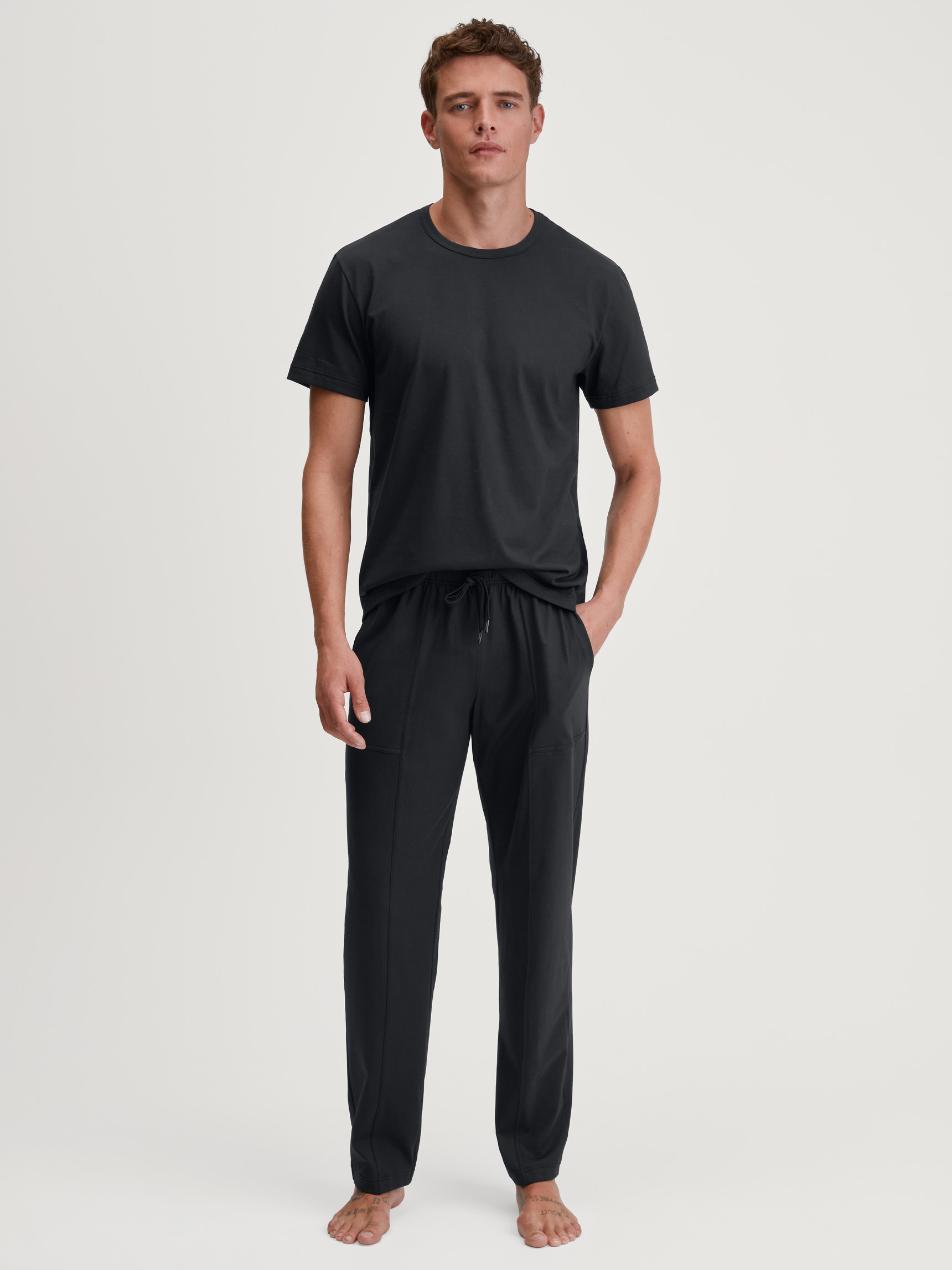 Herren-Model trägt Kurzarm-Shirt aus 100% Baumwolle in Schwarz, Einfarbig aus Serie RMX Sleep Leisure von CALIDA, Outfit