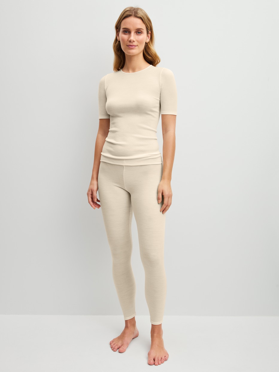 La modella / Il modello Donna indossa Maglietta a maniche corte in lana-seta in Lana di colore Beige, Tinta unita, della serie Silky Wool Soft di CALIDA, Abbigliamento