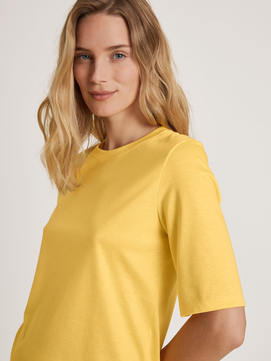Damen-Model trägt Kurzarm-Shirt aus Modal in Gelb, Einfarbig aus Serie Favourites Light von CALIDA, Detail