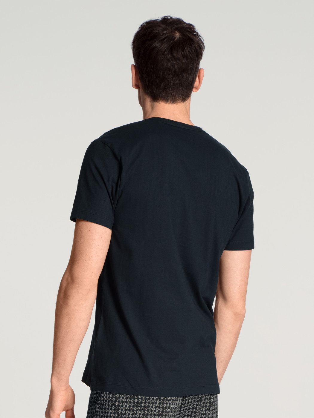 Herren-Model trägt Kurzarm-Shirt, V-Neck aus 100% Baumwolle in Blau, Einfarbig aus Serie Remix Basic Sleep von CALIDA, Rückansicht