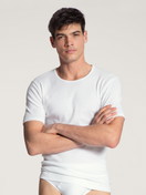 La modella / Il modello Uomo indossa T-shirt in 100% cotone di colore Bianco, Tinta unita, della serie Cotton 1:1 di CALIDA, Vista frontale