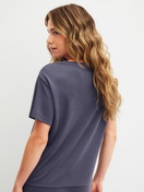 Damen-Model trägt Kurzarm-Shirt aus Modal in Blau, Einfarbig aus Serie Natural Loungewear von CALIDA, Rückansicht