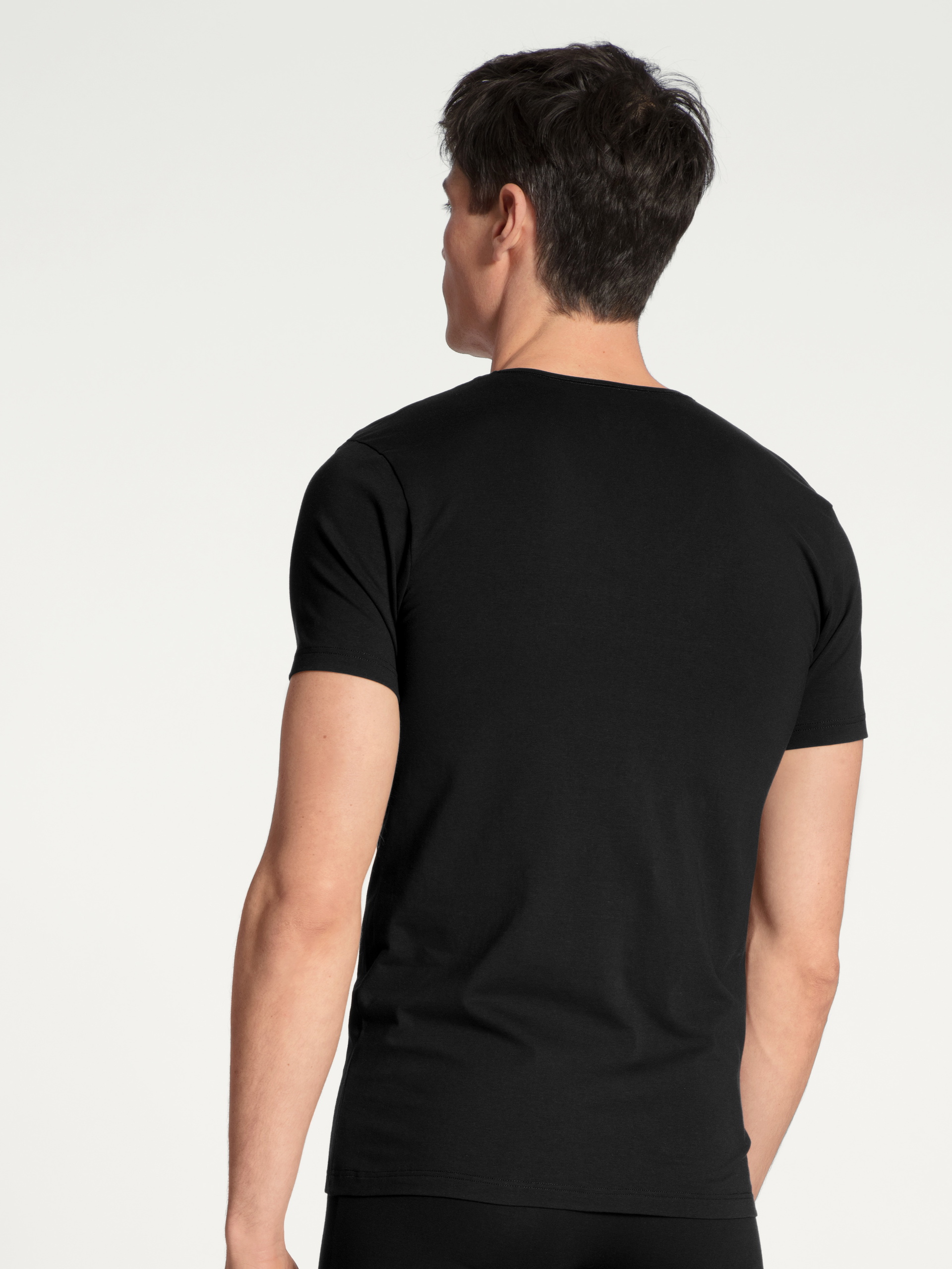 Herren-Model trägt T-Shirt, V-Neck aus Baumwolle in Schwarz, Einfarbig aus Serie Cotton Code von CALIDA, Rückansicht