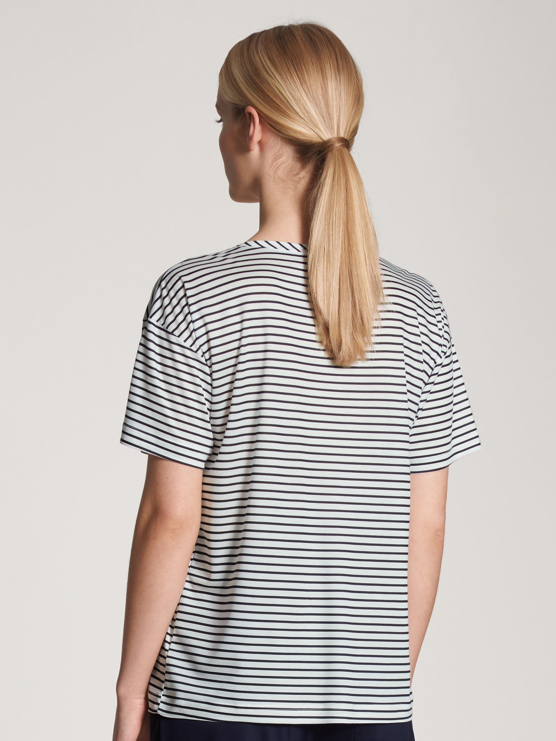 Damen-Model trägt Kurzarm-Shirt aus Lyocell in Blau, Gestreift aus Serie Circular Sleep von CALIDA, Rückansicht