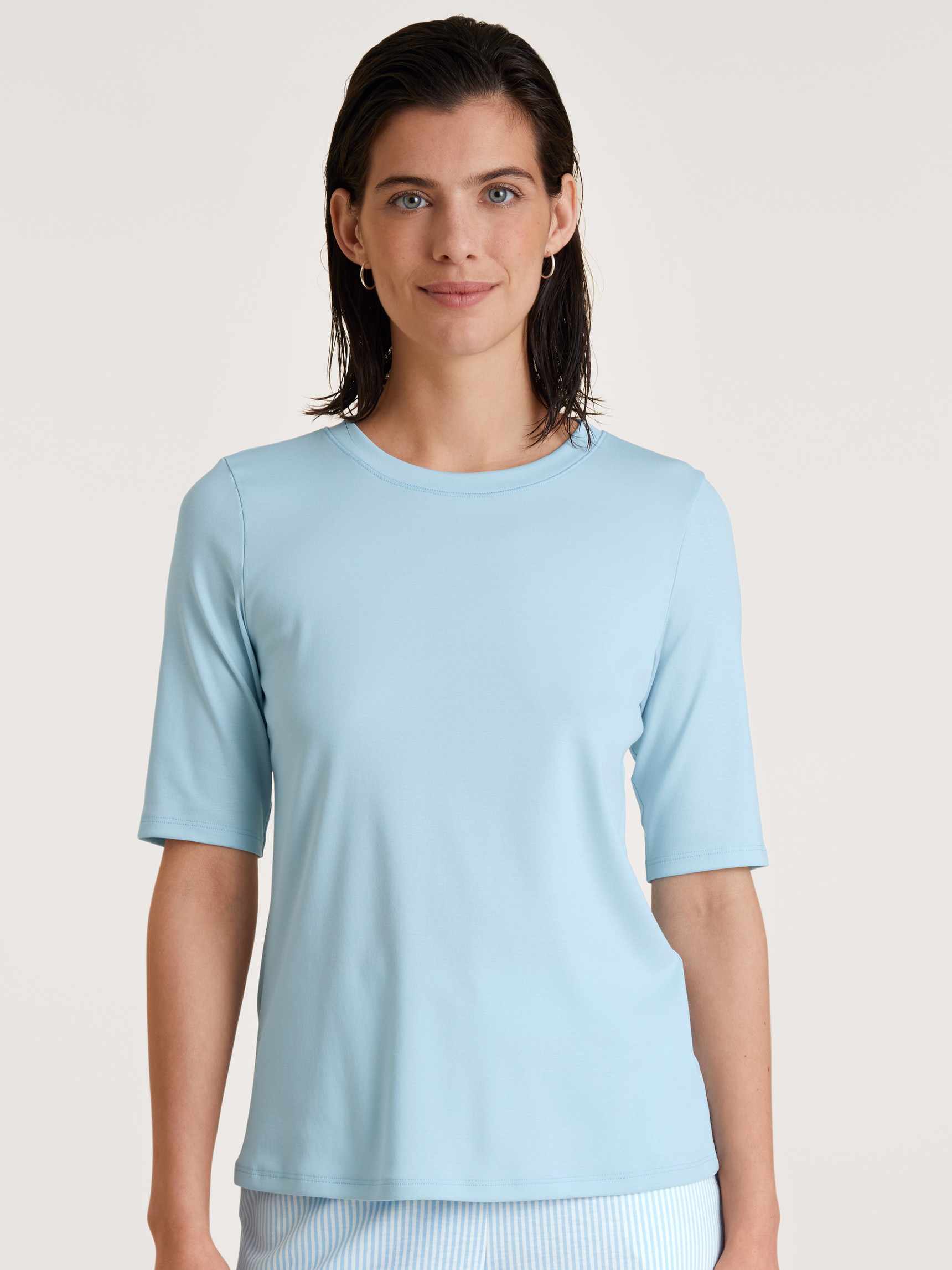 Damen-Model trägt Kurzarm-Shirt aus Baumwolle in Blau, Einfarbig aus Serie Amalfi Journey von CALIDA, Vorderansicht