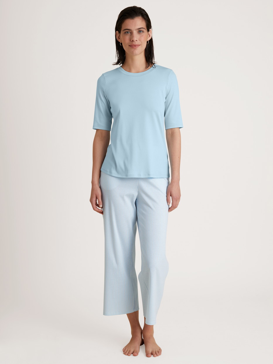 Damen-Model trägt Kurzarm-Shirt aus Baumwolle in Blau, Einfarbig aus Serie Amalfi Journey von CALIDA, Vorderansicht, Outfit