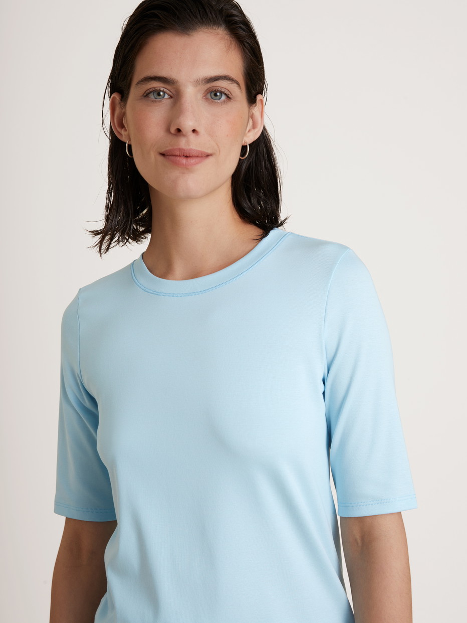Damen-Model trägt Kurzarm-Shirt aus Baumwolle in Blau, Einfarbig aus Serie Amalfi Journey von CALIDA, Detail