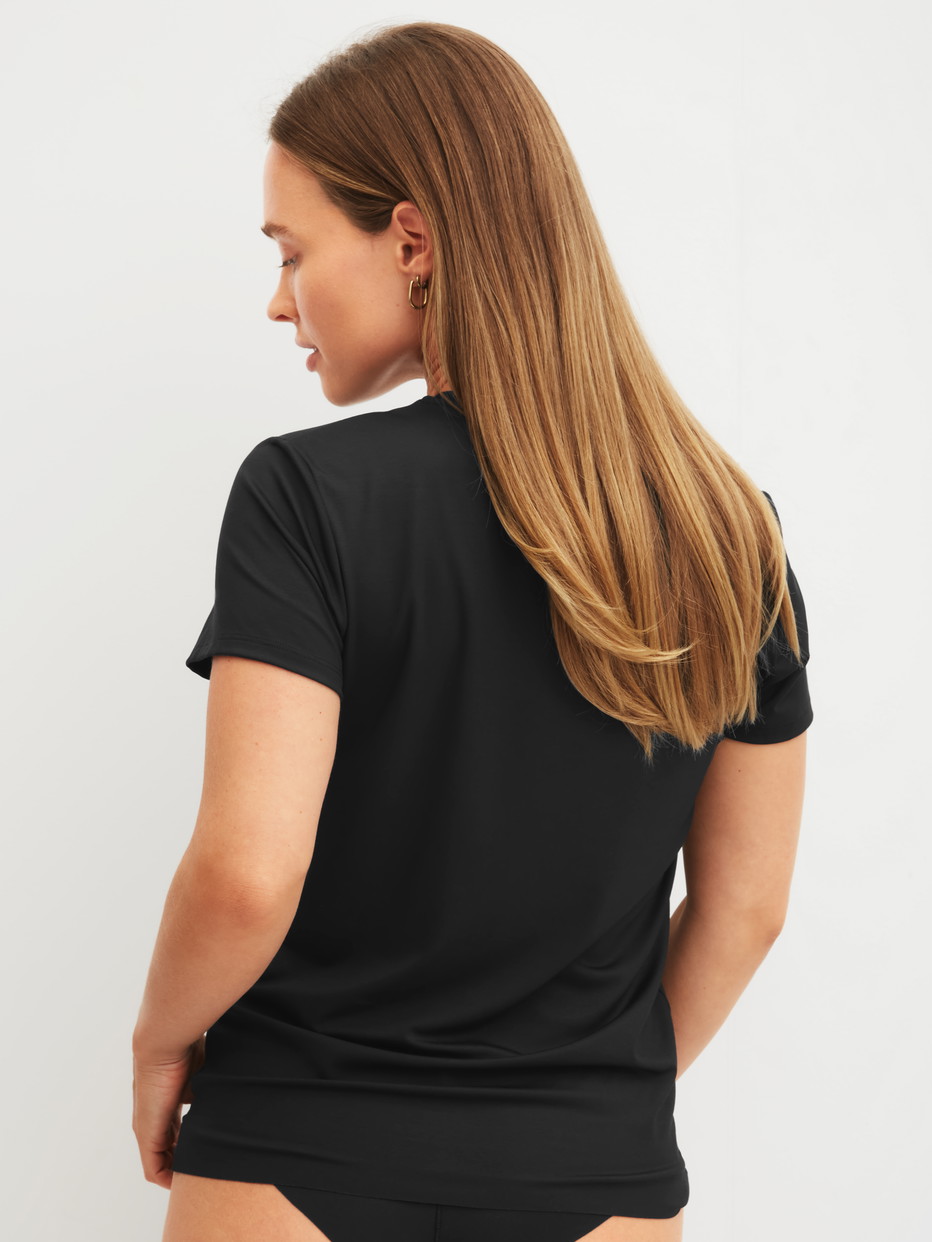 La modella / Il modello Donna indossa Shirt a manica corta in Modal di colore Nero, Tinta unita, della serie Natural Skin di CALIDA, Vista posteriore