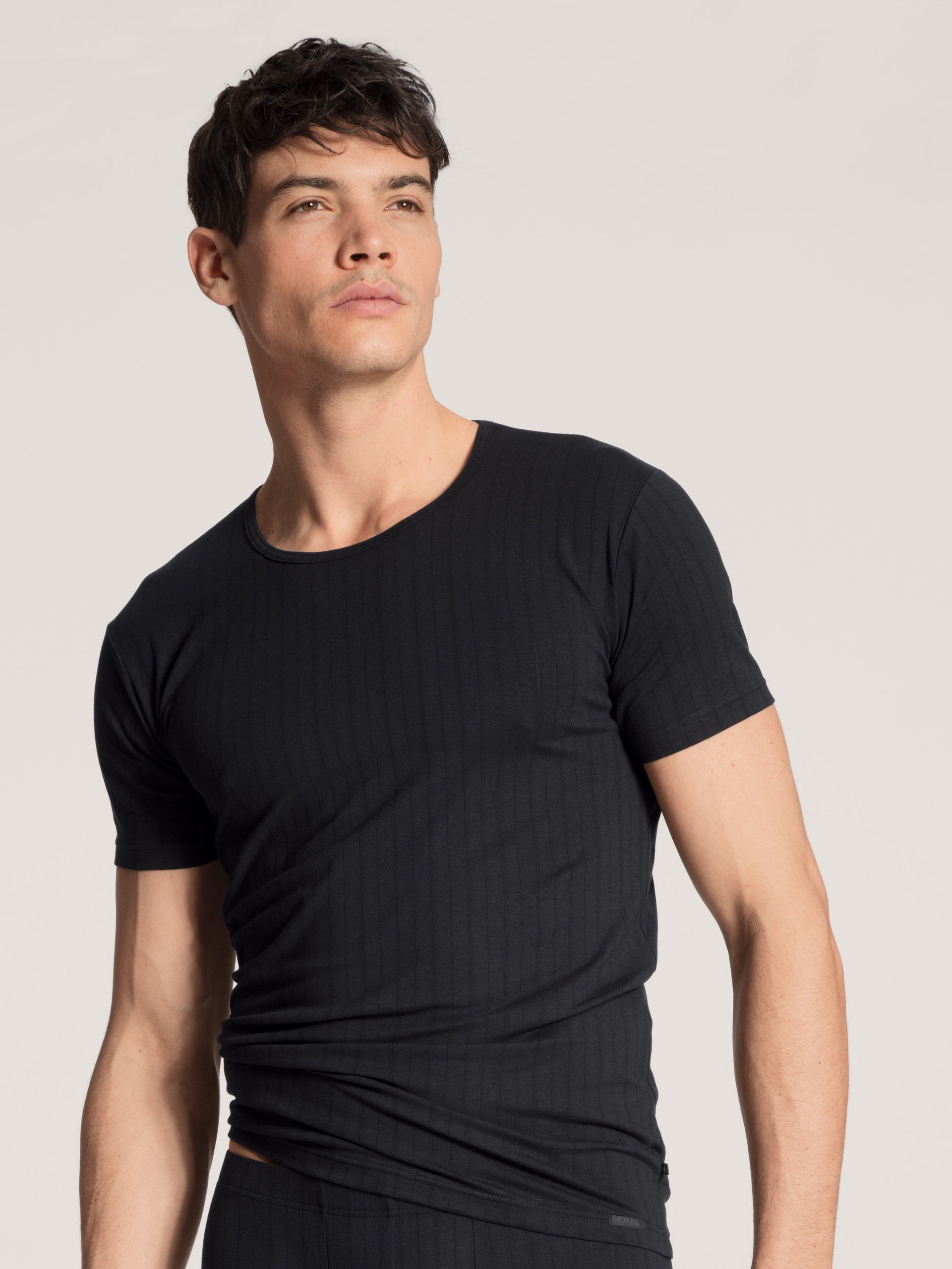 Herren-Model trägt T-Shirt, Rundhals aus Baumwolle in Schwarz, Einfarbig aus Serie Pure & Style von CALIDA, Vorderansicht