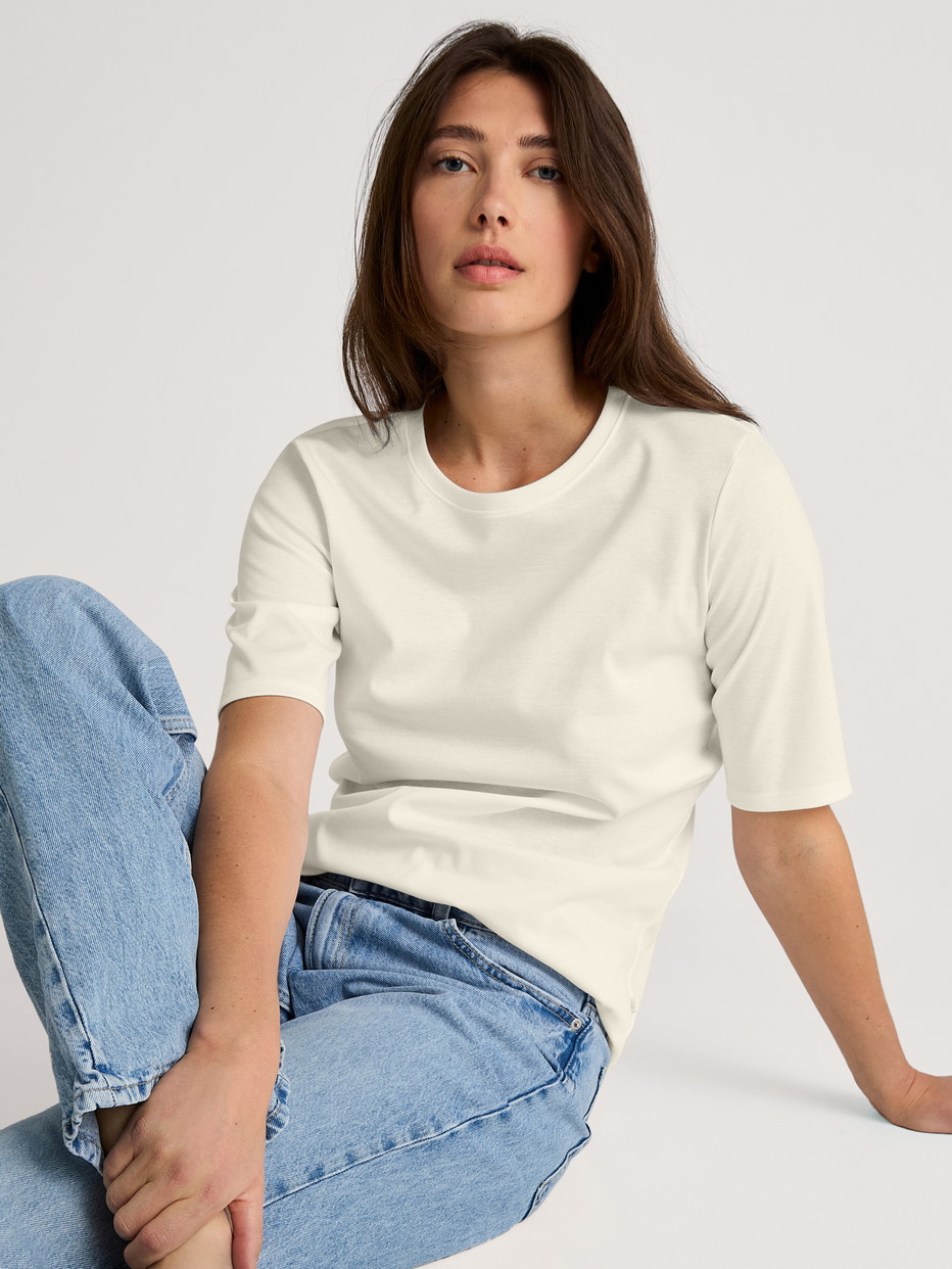 Women model is wearing Short-sleeved shirt made of 100% Cotton in White, Unicoloured from the Favourites Sleep series by CALIDA, Front view