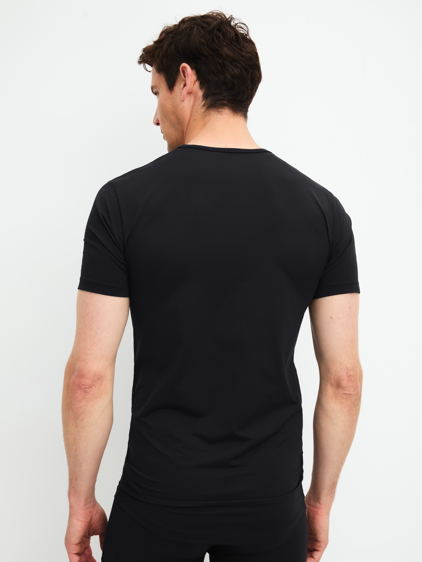 Herren-Model trägt Kurzarm-Shirt aus Polyamid in Schwarz, Einfarbig aus Serie Micro Stretch von CALIDA, Rückansicht