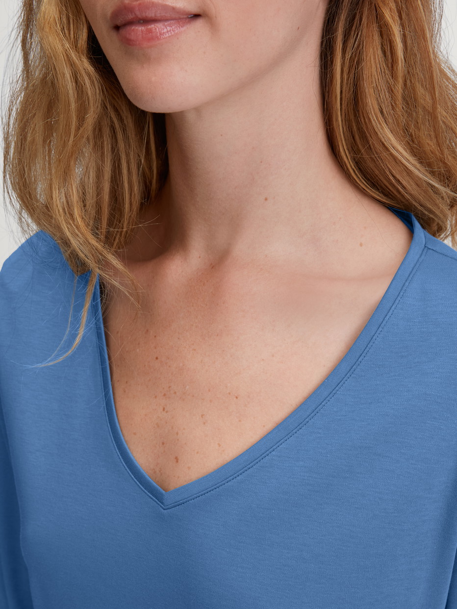 Damen-Model trägt Langarm-Shirt, V-Neck aus 100% Baumwolle in Blau, Einfarbig aus Serie Favourites Journey von CALIDA, Detail
