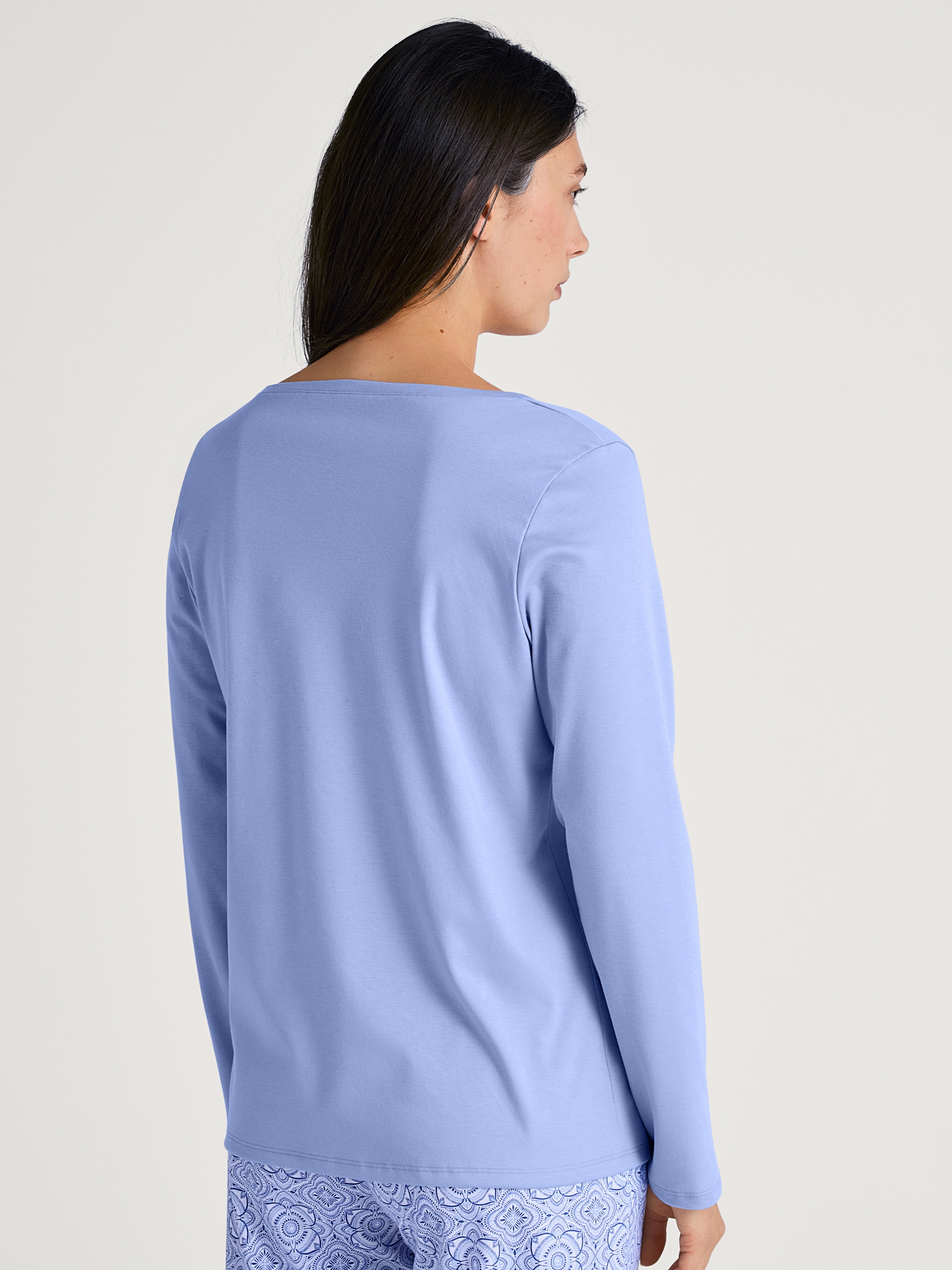 Damen-Model trägt Langarm-Shirt, V-Neck aus 100% Baumwolle in Blau, Einfarbig aus Serie Favourites Marine von CALIDA, Rückansicht