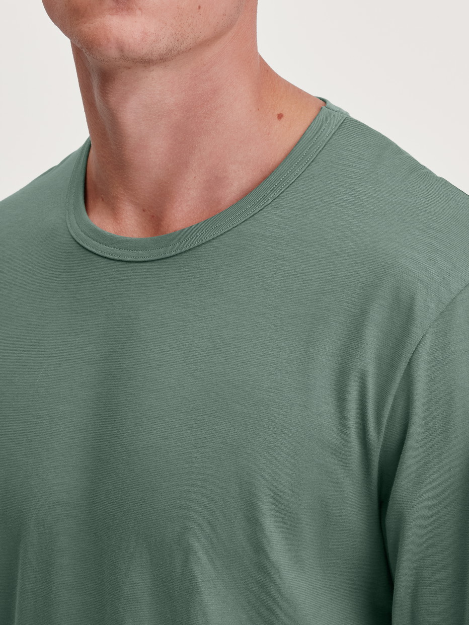 La modella / Il modello Uomo indossa Shirt a manica lunga in 100% cotone di colore Verde, Tinta unita, della serie RMX Sleep Weekend di CALIDA, Dettaglio