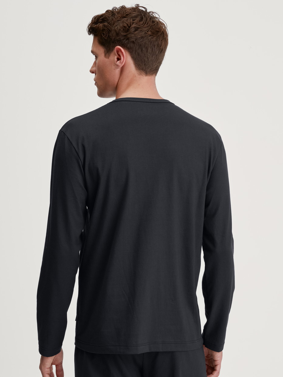 Herren-Model trägt Langarm-Shirt aus 100% Baumwolle in Schwarz, Einfarbig aus Serie RMX Sleep Leisure von CALIDA, Rückansicht