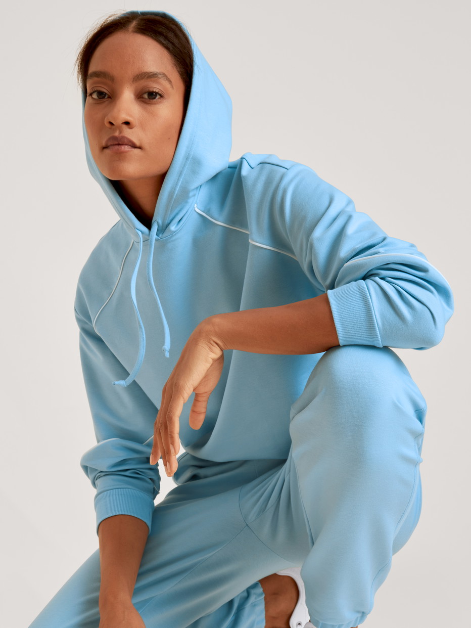 Damen-Model trägt Sweatshirt mit Kapuze aus Baumwolle in Blau, Einfarbig aus Serie Lounge Paisley von CALIDA, Vorderansicht