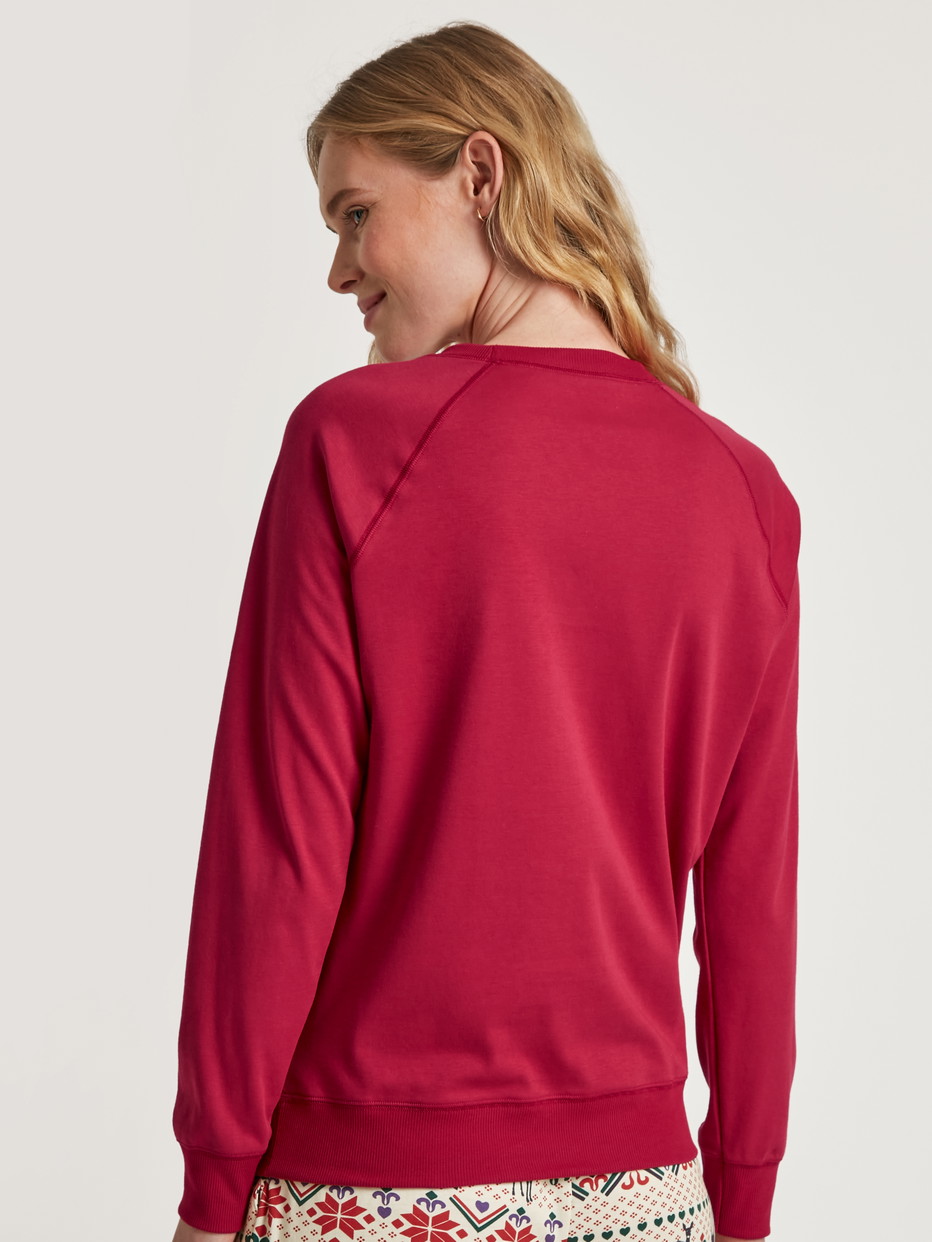 Damen-Model trägt Langarm-Shirt aus 100% Baumwolle in Rot, Einfarbig aus Serie Favourites Holidays von CALIDA, Rückansicht
