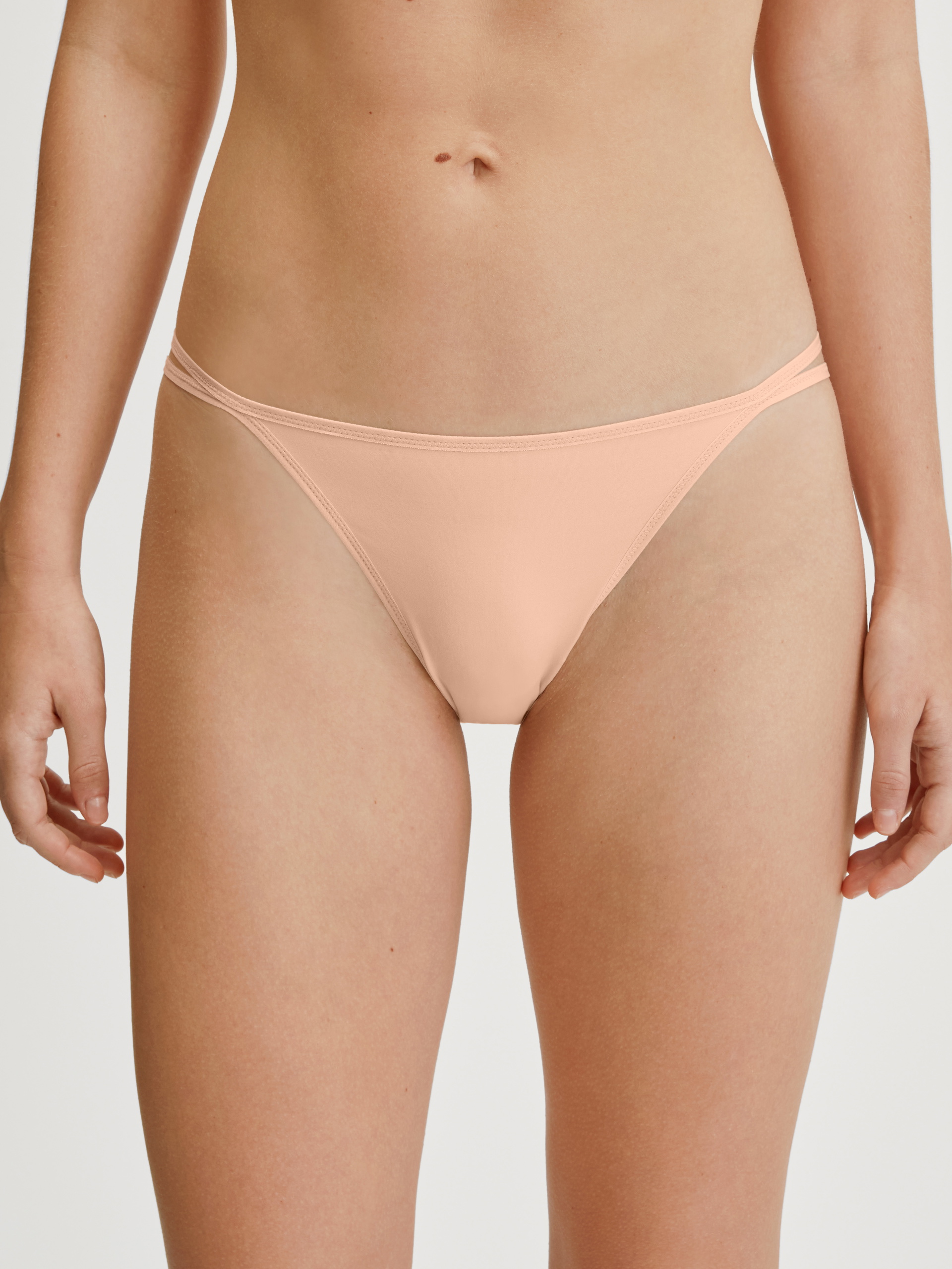Women model is wearing Low Cut Tanga Brief made of Polyamide in Beige, Unicoloured from the Sleek Skin series by CALIDA, Front view