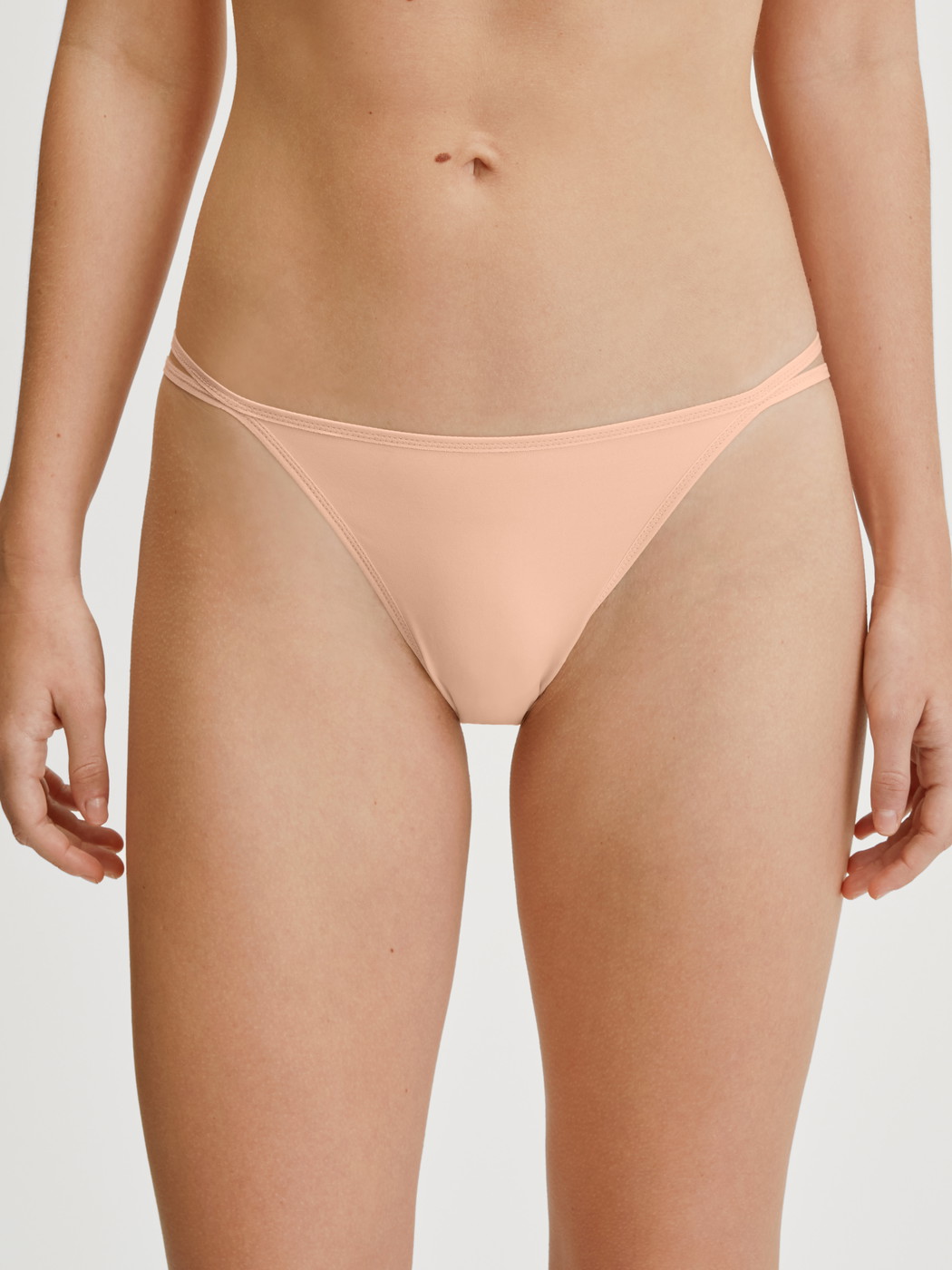Women model is wearing Low Cut Tanga Brief made of Polyamide in Beige, Unicoloured from the Sleek Skin series by CALIDA, Front view