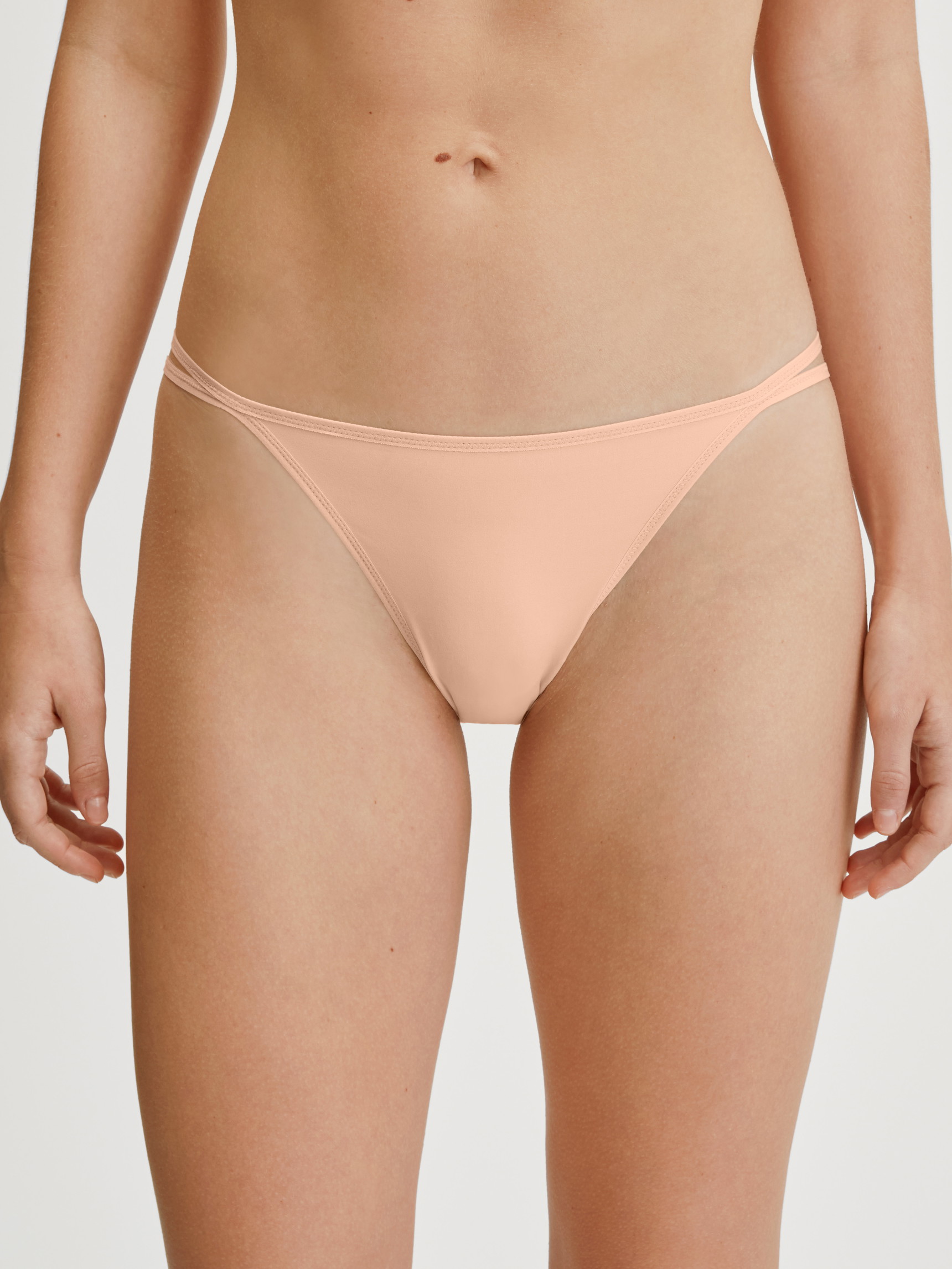 Le mannequin Femme porte le/la Tanga taille basse en Polyamide de couleur Beige, Unicolore, de la série Sleek Skin de CALIDA, Vue de face