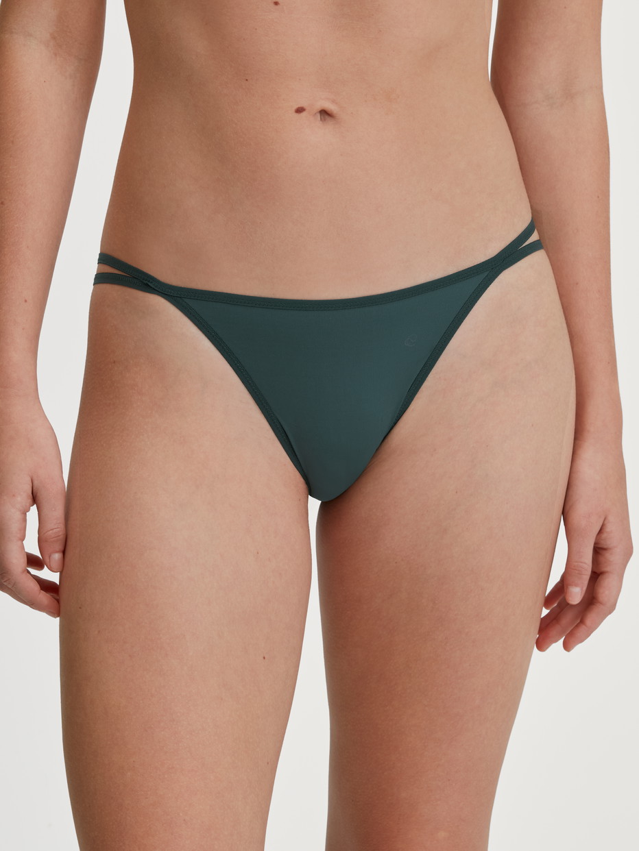 Damen-Model trägt Tanga-Slip, low cut aus Polyamid in Grün, Einfarbig aus Serie Sleek Skin von CALIDA, Vorderansicht