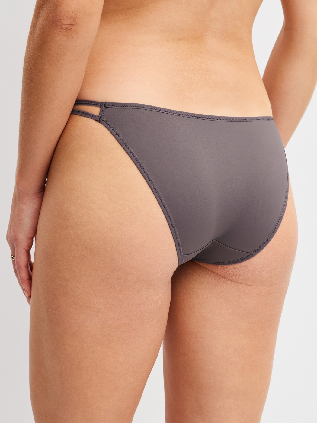 Women model is wearing Low Cut Tanga Brief made of Polyamide in Brown, Unicoloured from the Sleek Skin series by CALIDA, Back view