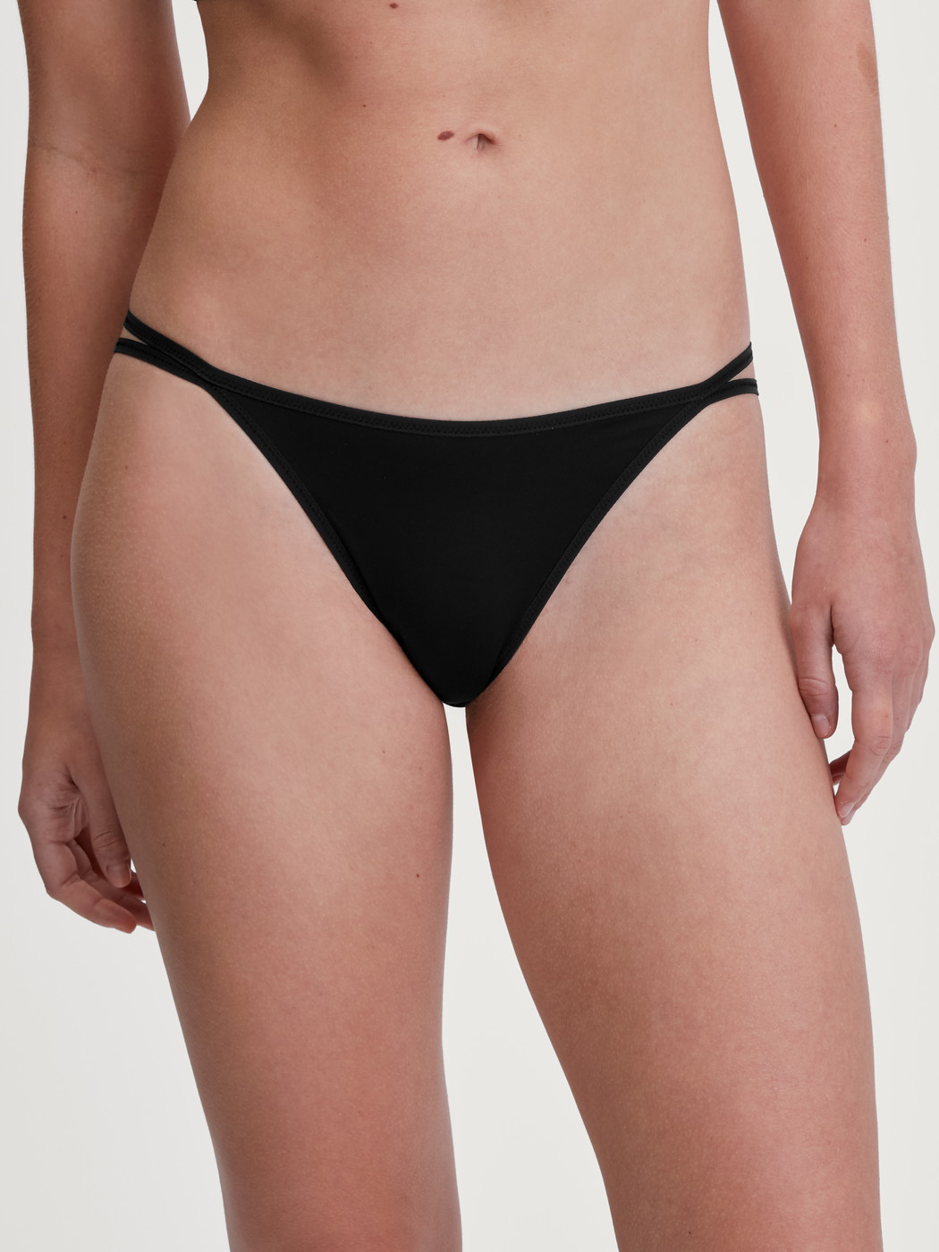 Women model is wearing Low Cut Tanga Brief made of Polyamide in Black, Unicoloured from the Sleek Skin series by CALIDA, Front view