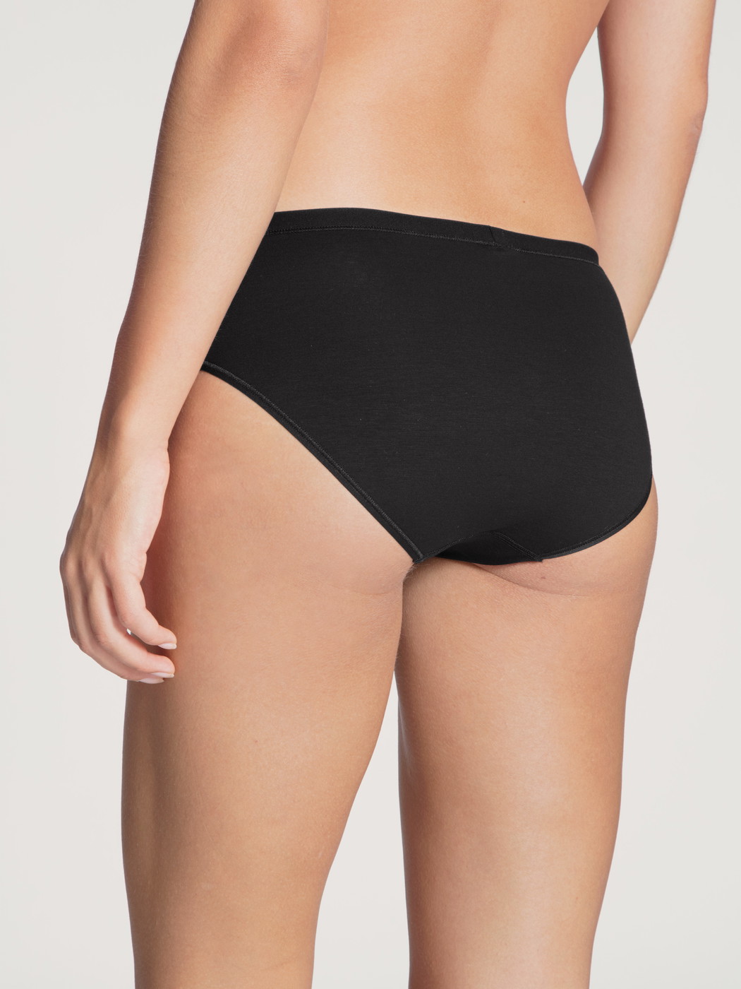 Damen-Model trägt Slip, regular cut aus Baumwolle in Schwarz, Einfarbig aus Serie Natural Comfort von CALIDA, Rückansicht
