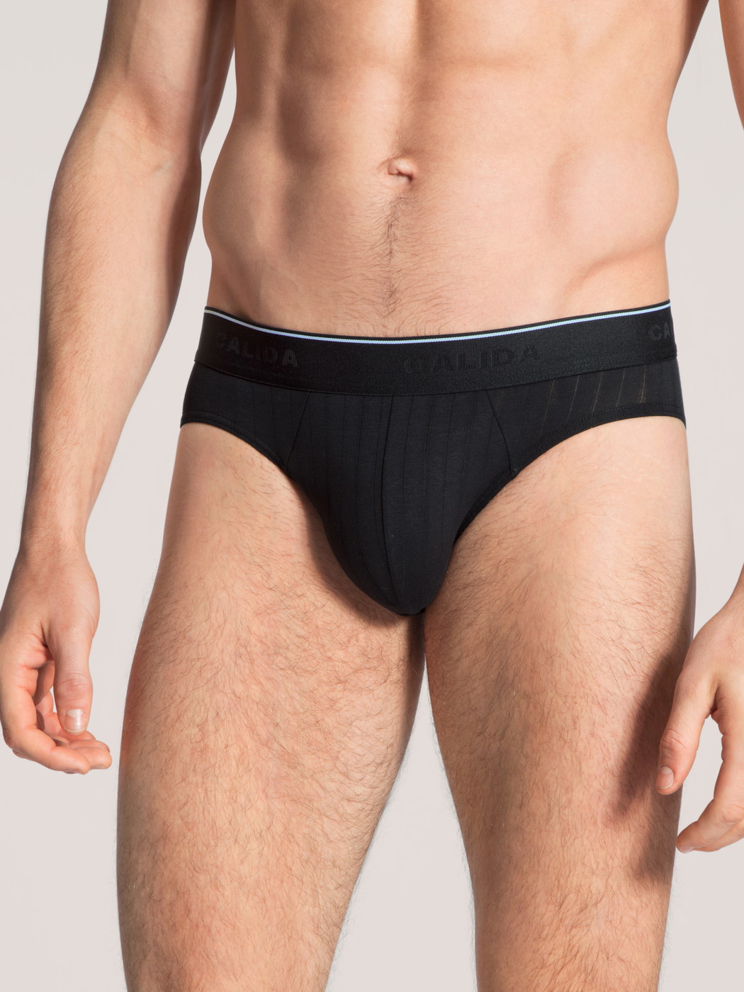 Herren-Model trägt Mini-Slip, Elastikbund aus Baumwolle in Schwarz, Einfarbig aus Serie Pure & Style von CALIDA, Vorderansicht