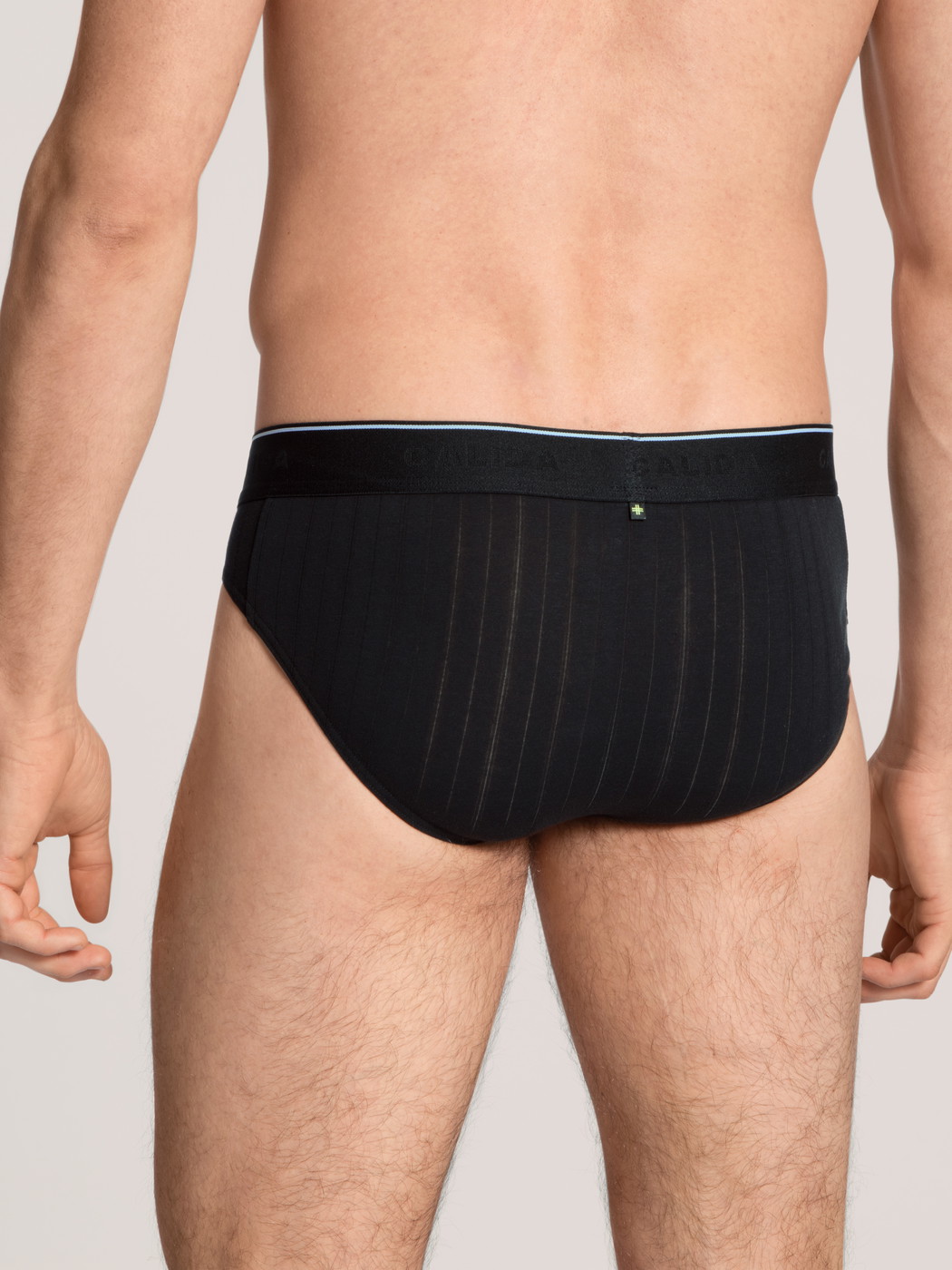 Herren-Model trägt Mini-Slip, Elastikbund aus Baumwolle in Schwarz, Einfarbig aus Serie Pure & Style von CALIDA, Rückansicht