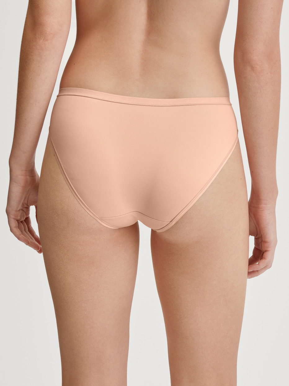 Damen-Model trägt Slip, regular cut aus Polyamid in Beige, Einfarbig aus Serie Sleek Skin von CALIDA, Rückansicht