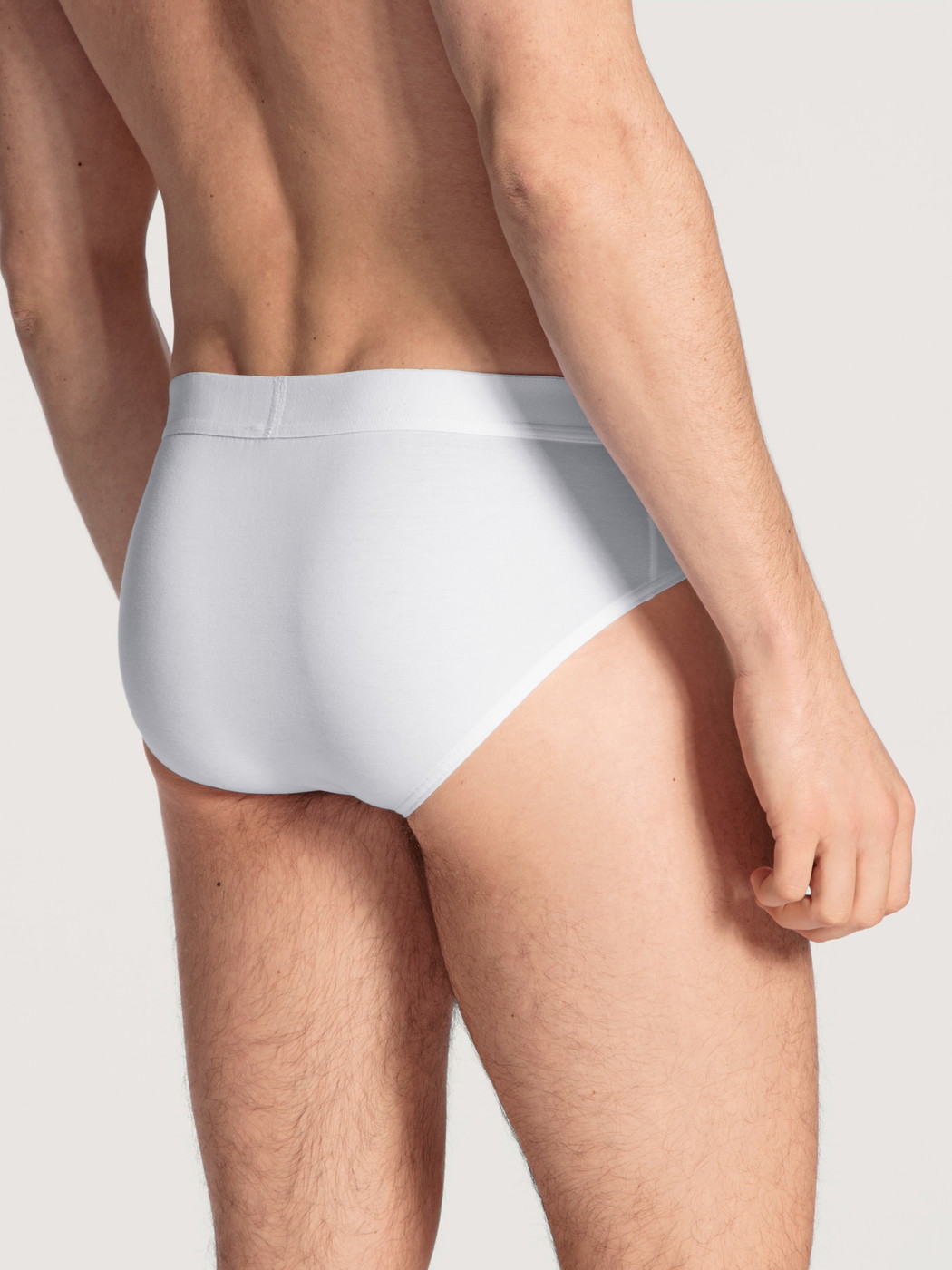 Herren-Model trägt Slip mit Elastikbund aus Baumwolle in Weiß, Einfarbig aus Serie Cotton Code von CALIDA, Rückansicht