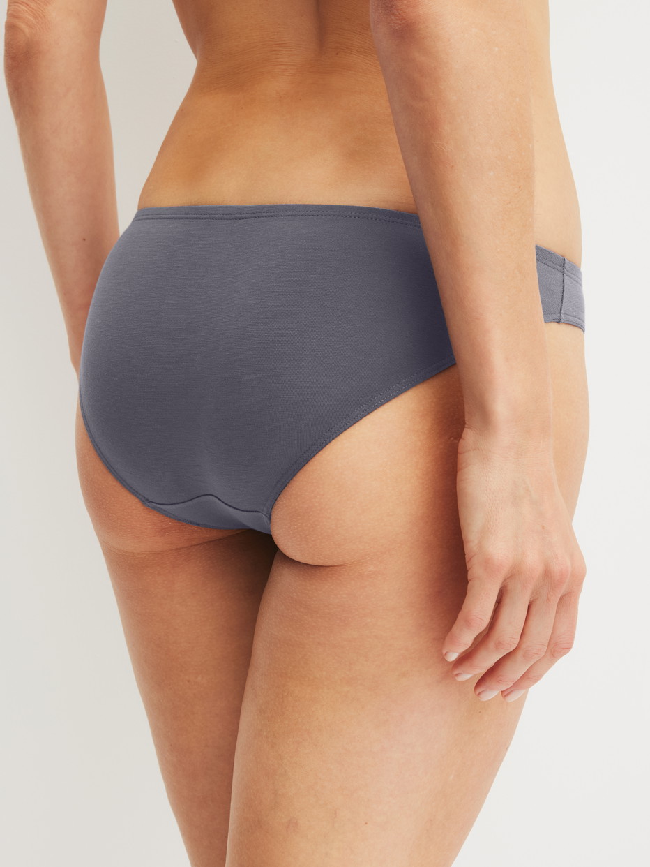 Damen-Model trägt Slip, low cut aus Baumwolle in Grau, Einfarbig aus Serie Essential Cotton von CALIDA, Rückansicht
