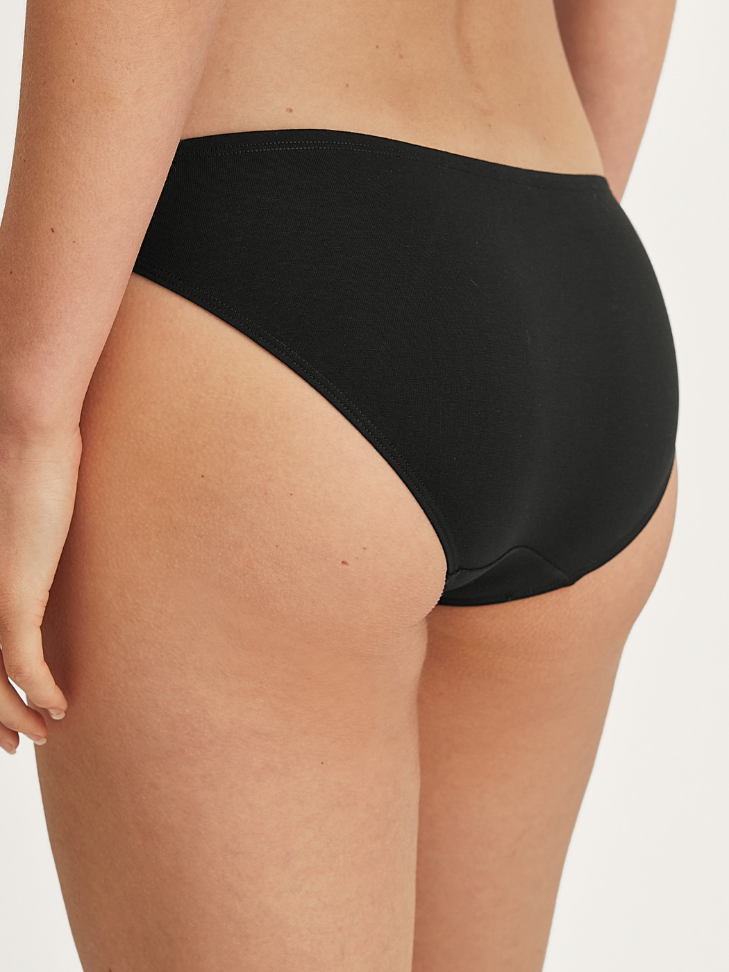 La modella / Il modello Donna indossa Slip in Cotone di colore Nero, Tinta unita, della serie Essential Cotton di CALIDA, Vista posteriore