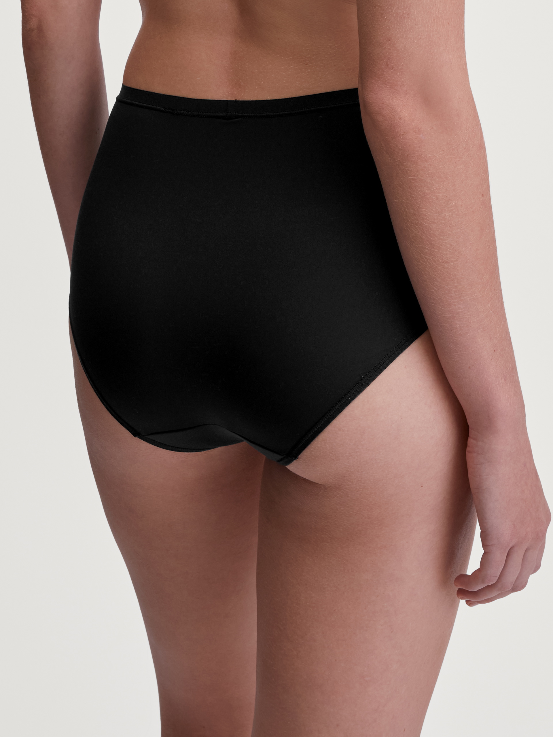 La modella / Il modello Donna indossa Slip, high waist in Poliammide di colore Nero, Tinta unita, della serie Sleek Skin di CALIDA, Vista posteriore