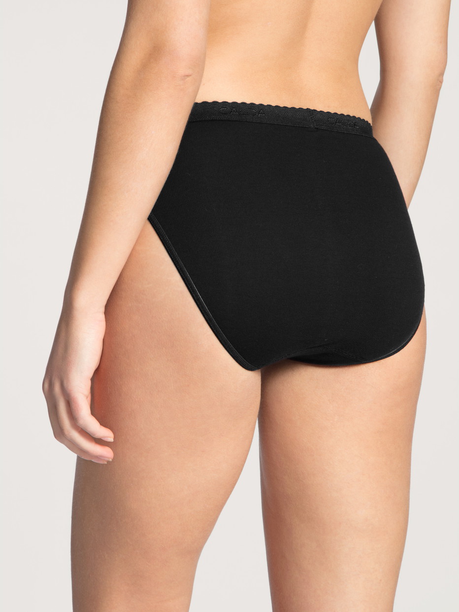 Damen-Model trägt Minislip aus 100% Baumwolle in Schwarz, Einfarbig aus Serie Iconics von CALIDA, Rückansicht