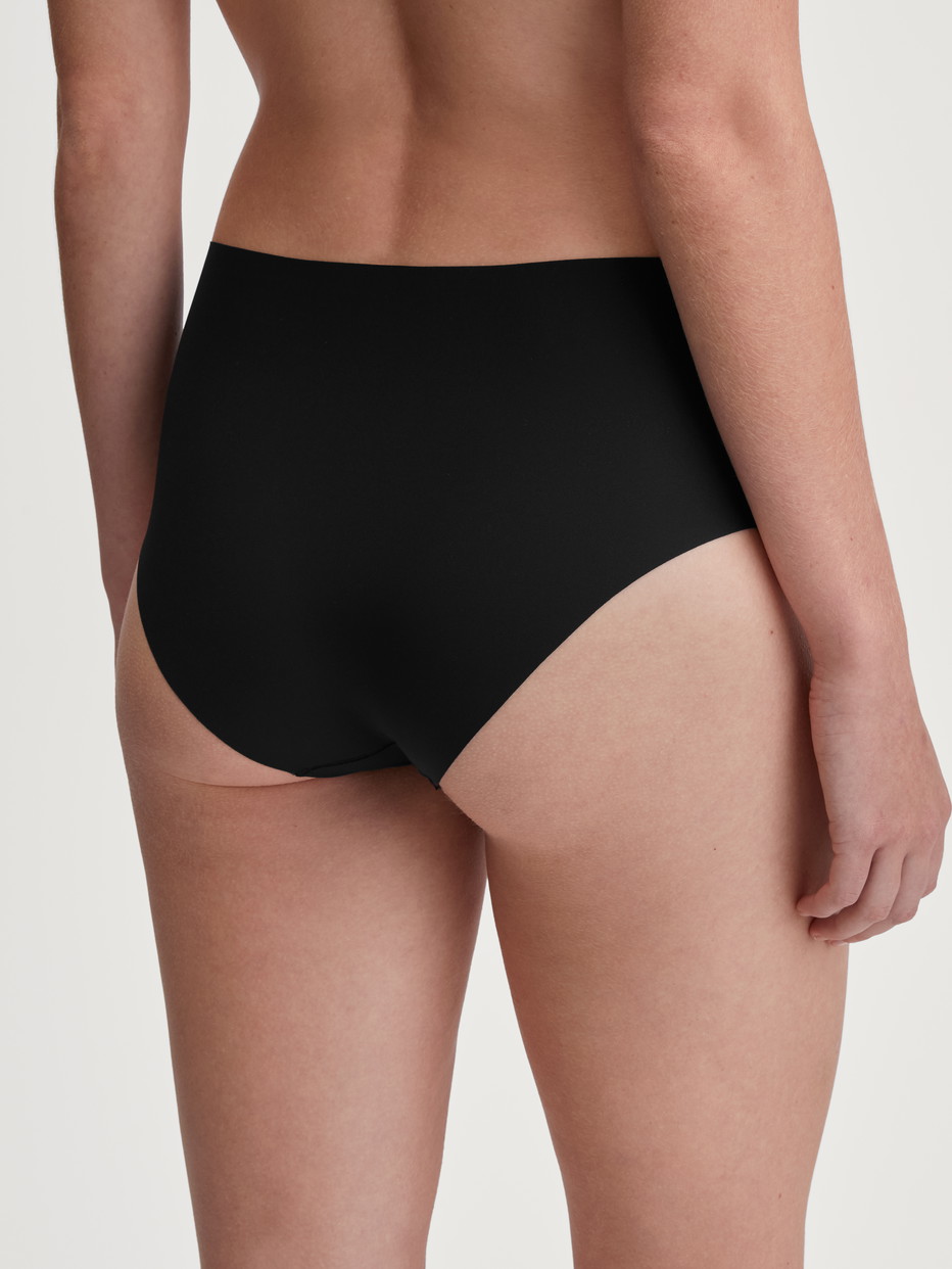 Damen-Model trägt Nahtloser Midi-Slip, Clean-Cut aus Polyamid in Schwarz, Einfarbig aus Serie Sleek Skin von CALIDA, Rückansicht