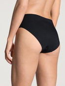 Damen-Model trägt Seamless-Midi-Slip aus Modal in Schwarz, Einfarbig aus Serie Natural Skin von CALIDA, Rückansicht