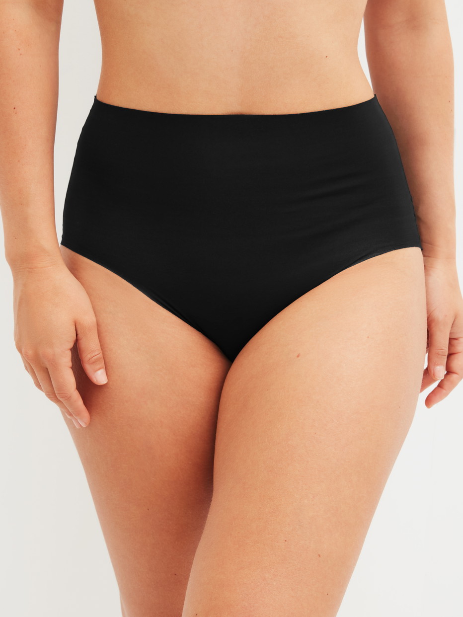 Damen-Model trägt Seamless High-Waist Slip aus Modal in Schwarz, Einfarbig aus Serie Natural Skin von CALIDA, Vorderansicht