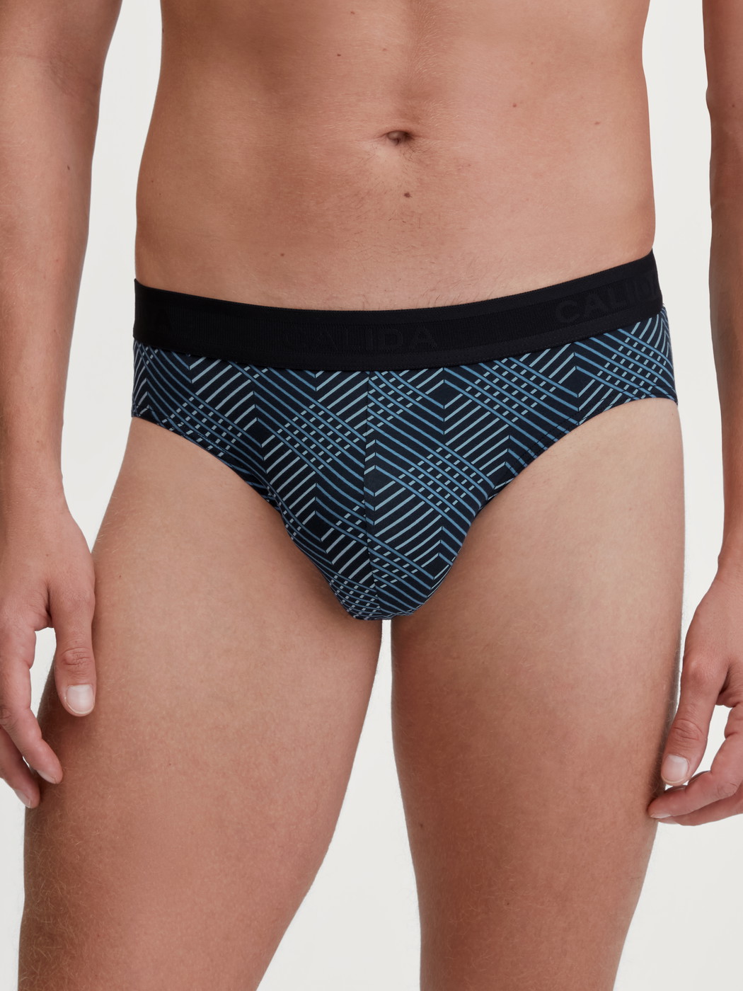 Herren-Model trägt Slip mit Softgummibund aus Baumwolle in Schwarz, Gemustert aus Serie Grafic Cotton von CALIDA, Vorderansicht